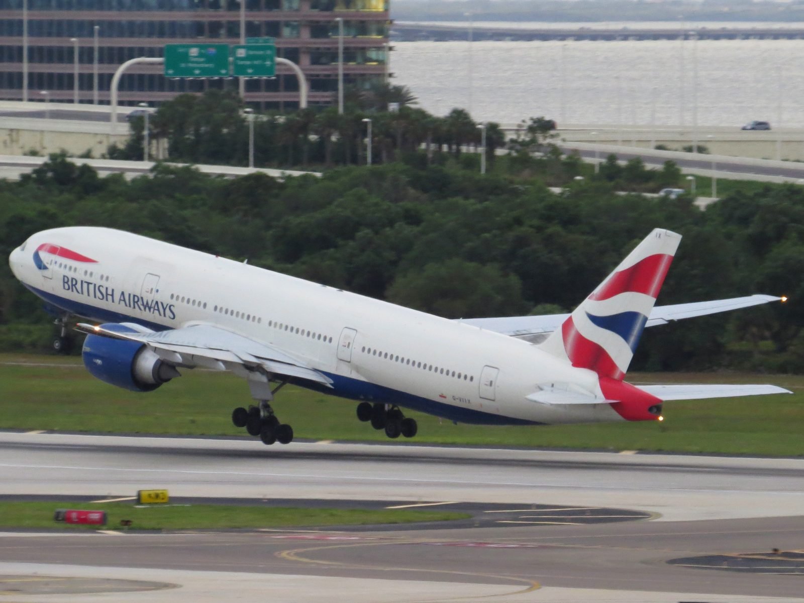 A British Airways Boeing 777-200ER lifting off from a runway, gear still down.