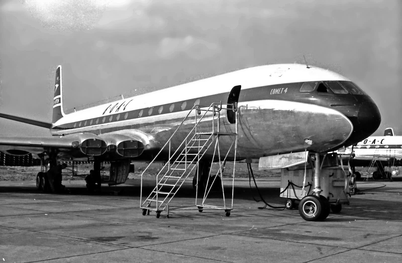 A BOAC de Havilland Comet 4 on stand at London Airport in July 1959, with boarding steps at the forward door, in black and white.