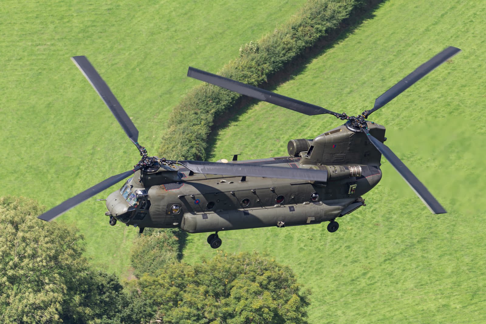 An RAF Boeing Chinook HC.6 flying low through a Welsh valley, its two rotors blurred.