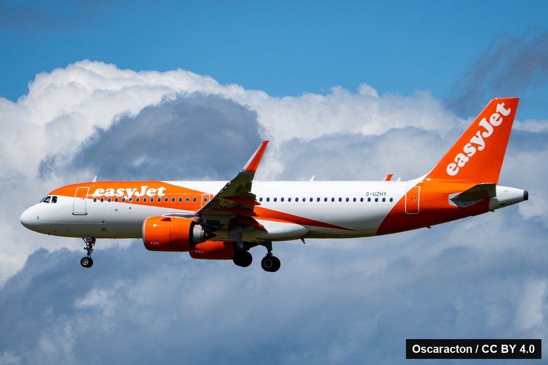 An easyJet Airbus A320neo in orange and white arriving at Edinburgh under a sky of large white clouds.