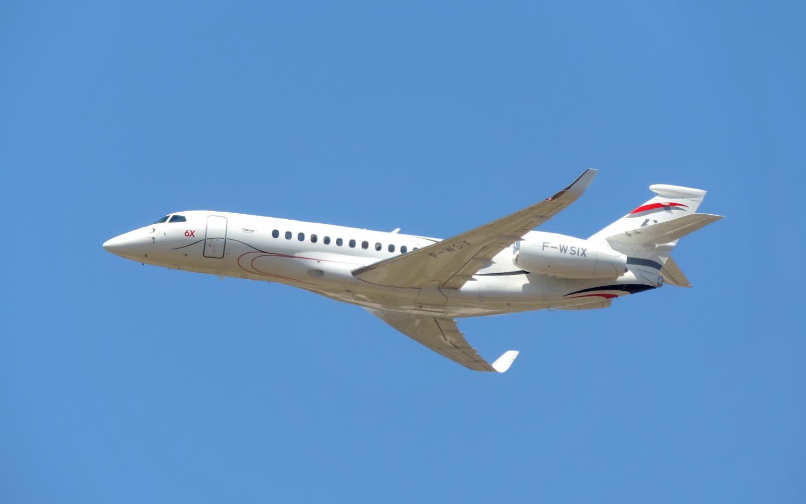 A Dassault Falcon 6X business jet, F-WSIX, climbing against a blue sky. It is another Falcon 6X, not the Irish Air Corps aircraft.